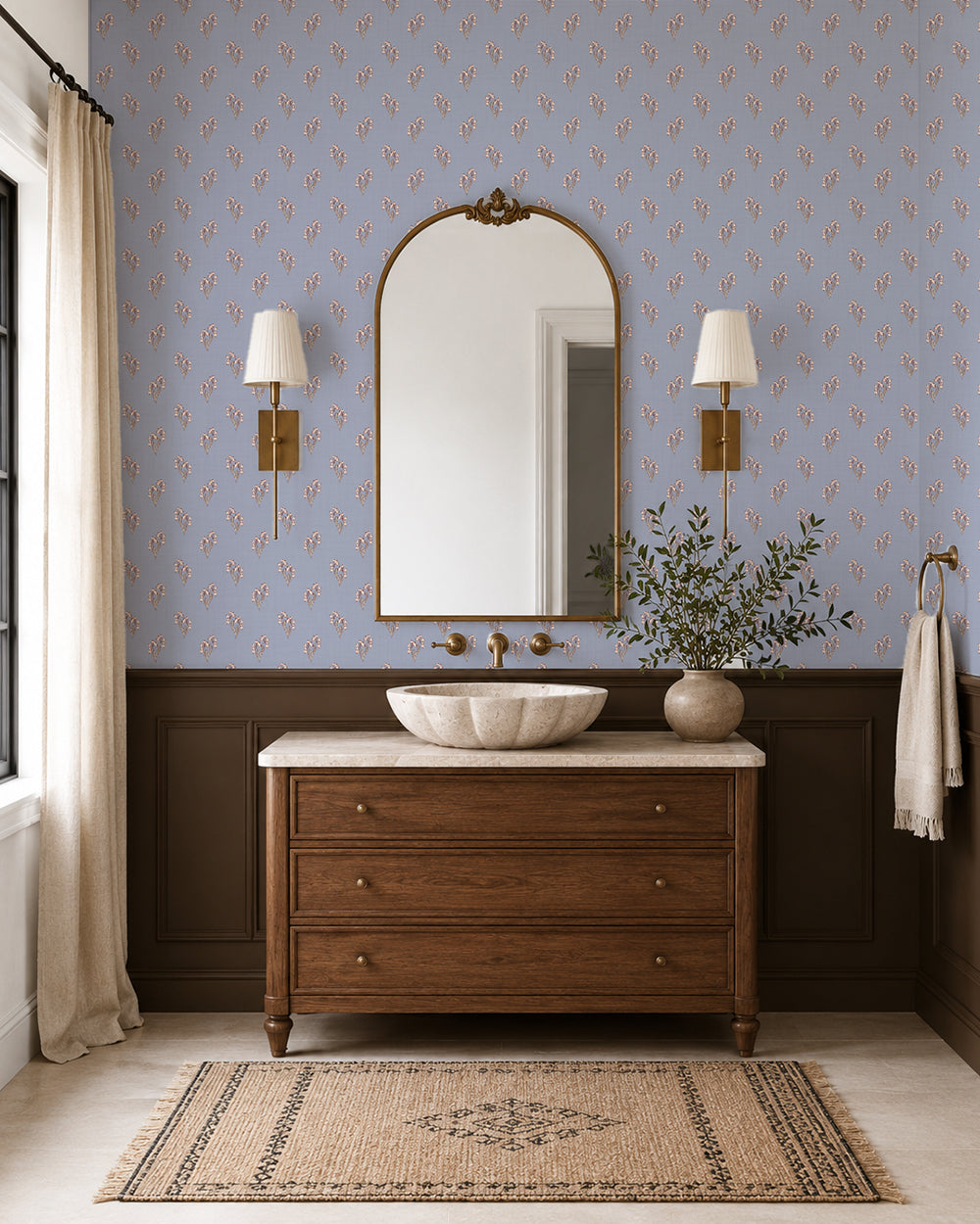 Foraged Bloom Dusty Blue wallpaper in an elegant bathroom with a wood vanity, brass sconces and dark wainscoting.