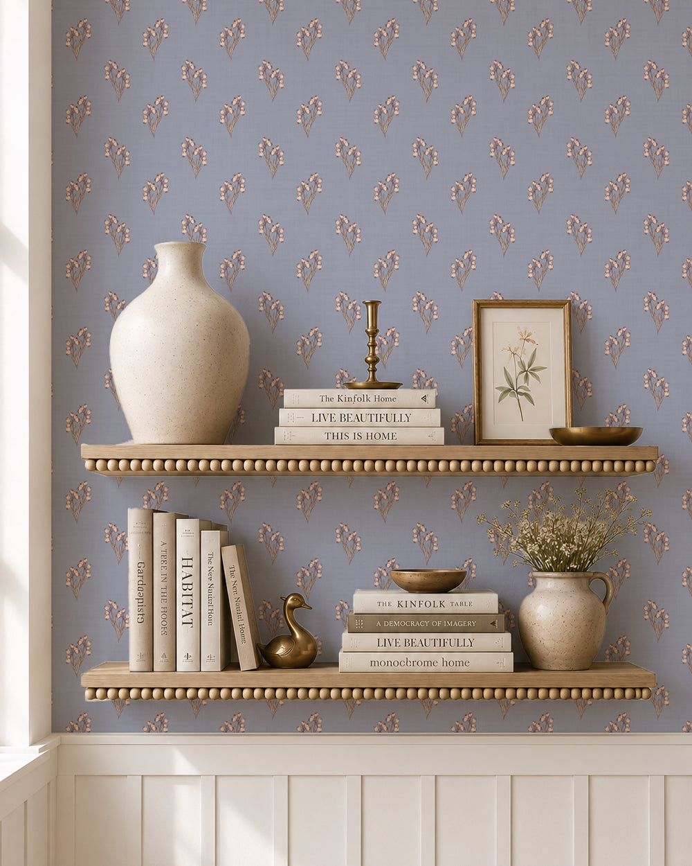 Foraged Bloom Dusty Blue wallpaper behind styled shelves with books, pottery and warm decorative accents.