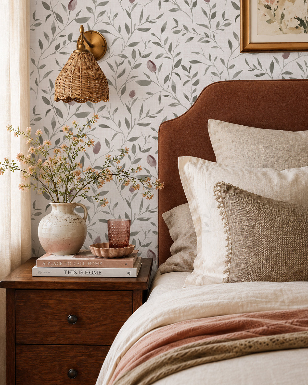 Rosebud Trail wallpaper with mauve rosebuds and soft green leaves in a warm bedroom with cream bedding and wood furniture.