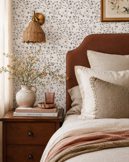 Spring Vine Bluebell Cream wallpaper in a warm bedroom with a rust headboard, cream bedding and dark wood furniture.
